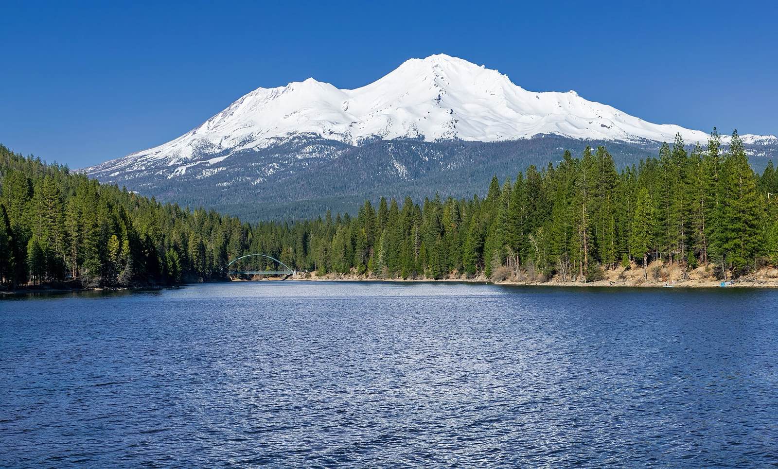 View across the still water of Lake Siskiyou to the snow-capped peak of Mount Shasta, with a footbridge in the foreground, Siskiyou County, California