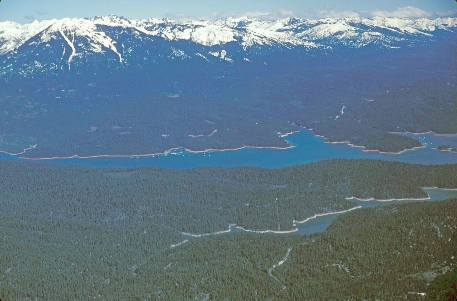 Aerial view of the deep blue waters of Trinity Lake with the snow-capped peaks of the Trinity Alps rising in the background, Trinity County, California