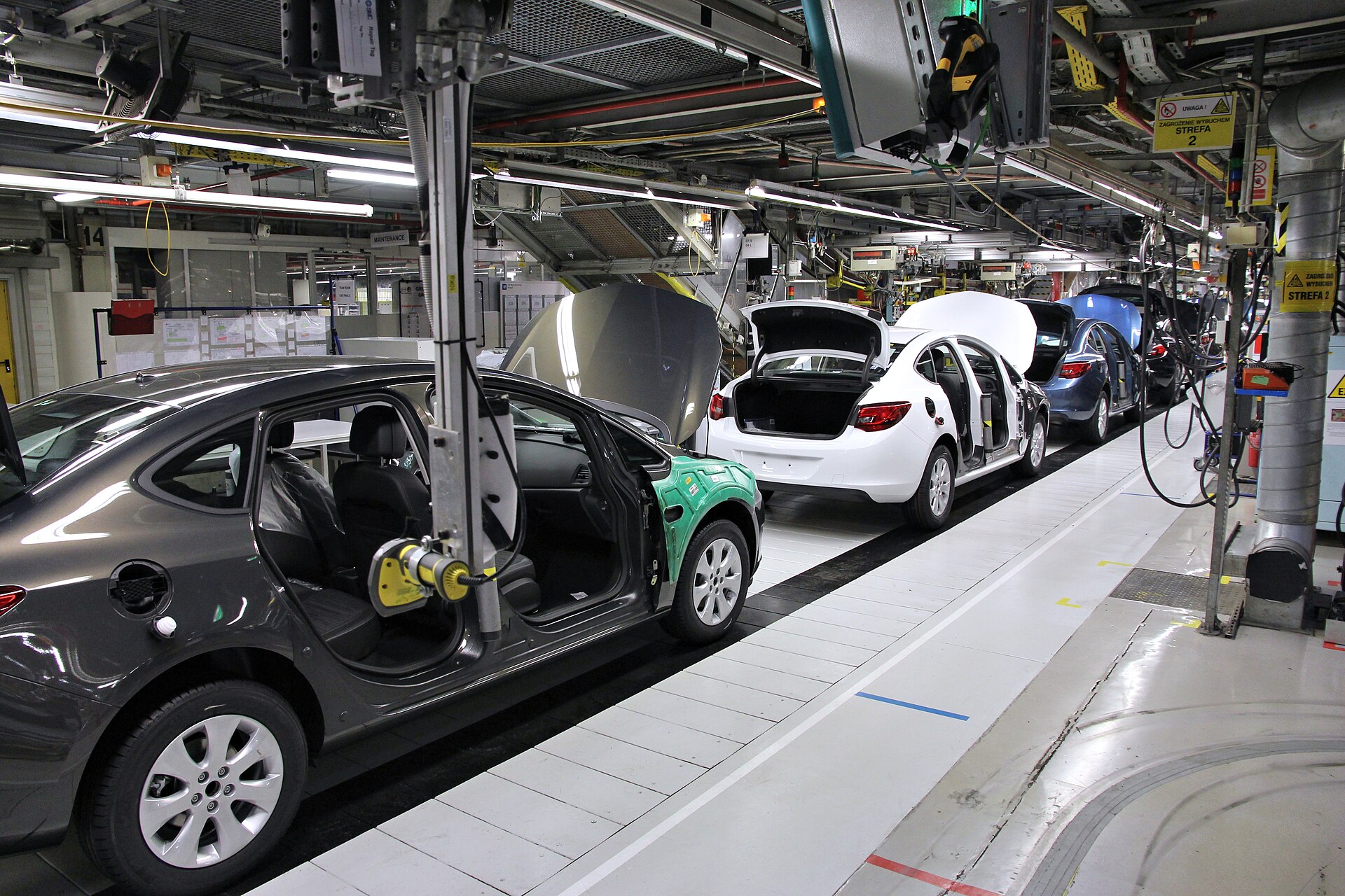 Cars moving down an automated assembly line inside a manufacturing plant.