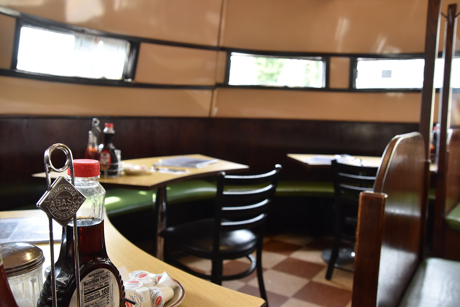 Booth seating and a table set with condiments inside a vintage American diner.